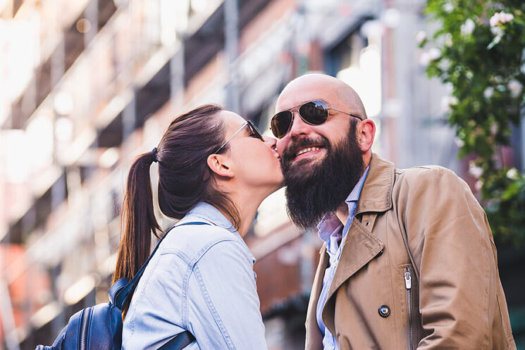 Image shows woman kissing face of smiling man
