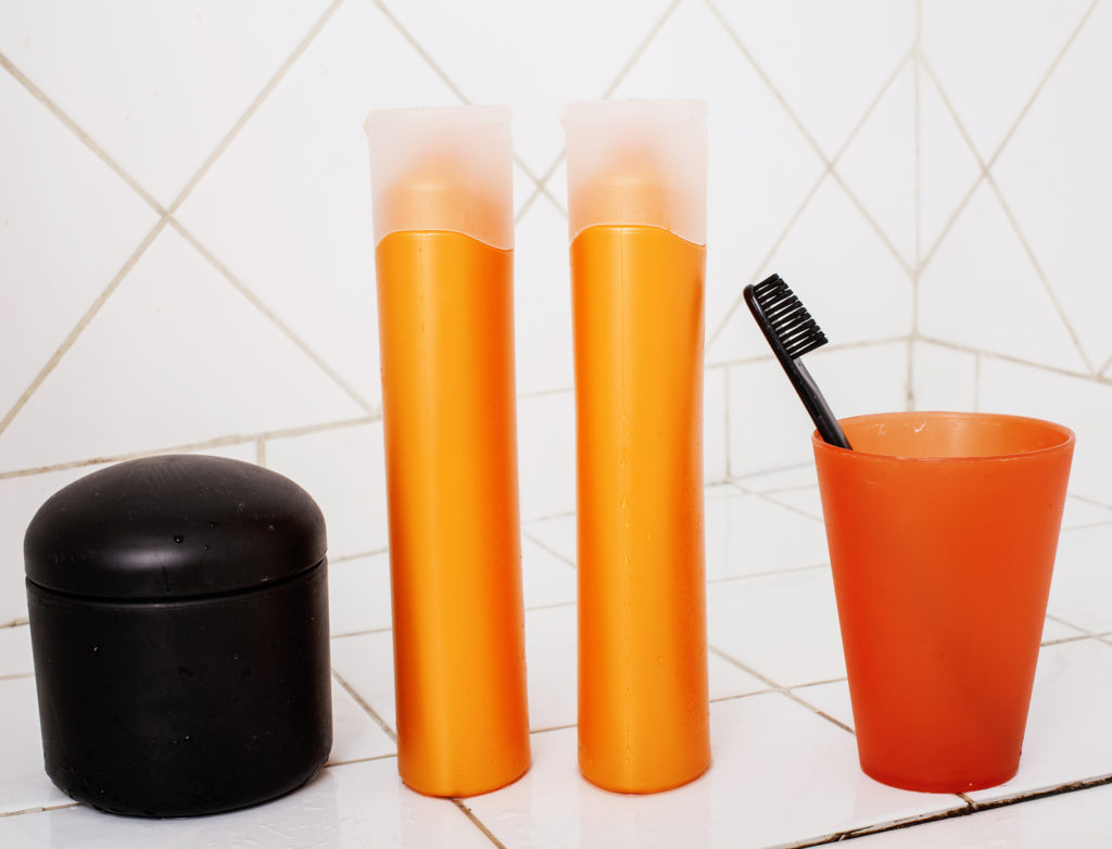A toothbrush, shampoo bottles, and other bathroom vanities on a tiled background. 