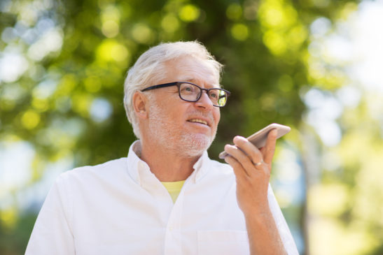 Older man using smartphone at park during the summer