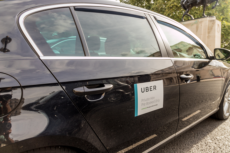 View of the left side of a black care with Uber sticker. 