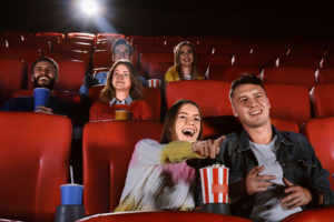 People sitting and excited, watching a movie in a movie theater.