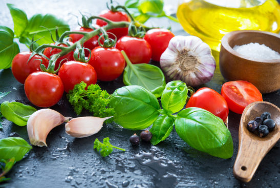 Ripe tomatoes with fresh basil, garlic and herbs a plate.