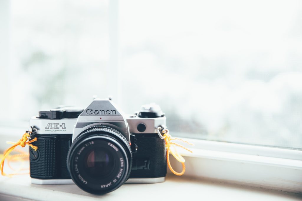 Digital camera against the window sill, with yellow strap.