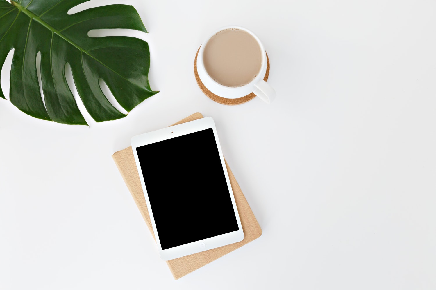 iPad with Coffee Cup and Leaf On a White Table