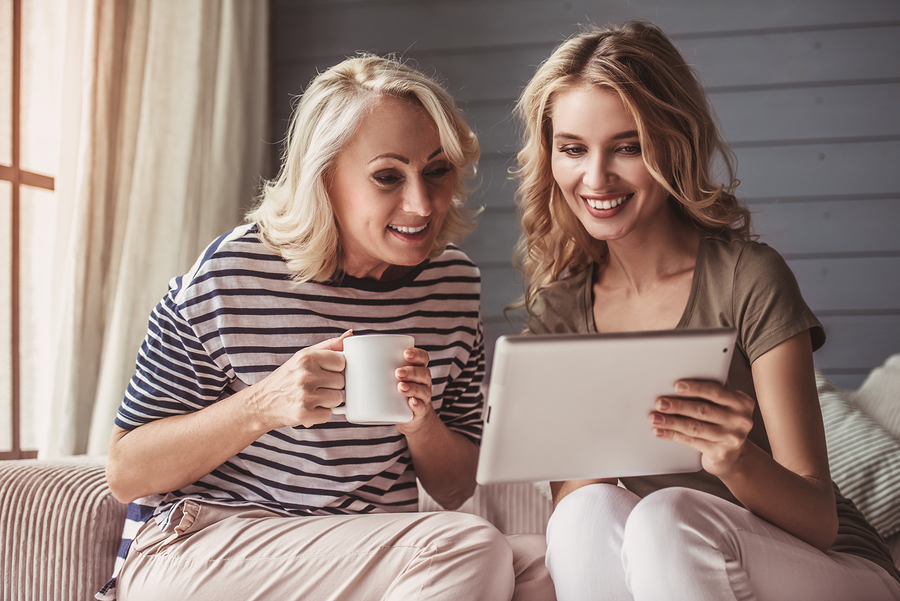 Mom and daughter smiling using a digital tablet.