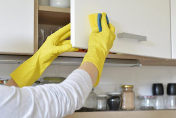 Image of hands in rubber gloves washing dishes.