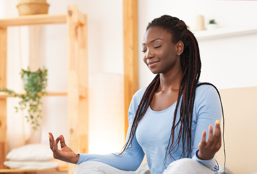 Image shows peaceful woman meditating in the lotus position.