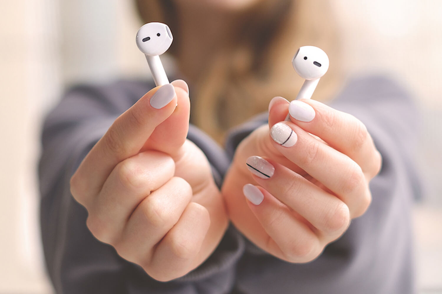 Hands holding AirPods.