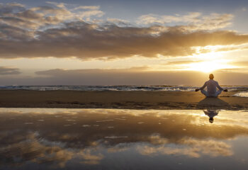 Image shows man in mediation at sunrise.