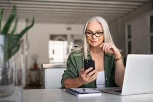 Stylish mature woman practicing VoiceOver gestures on her iPhone.