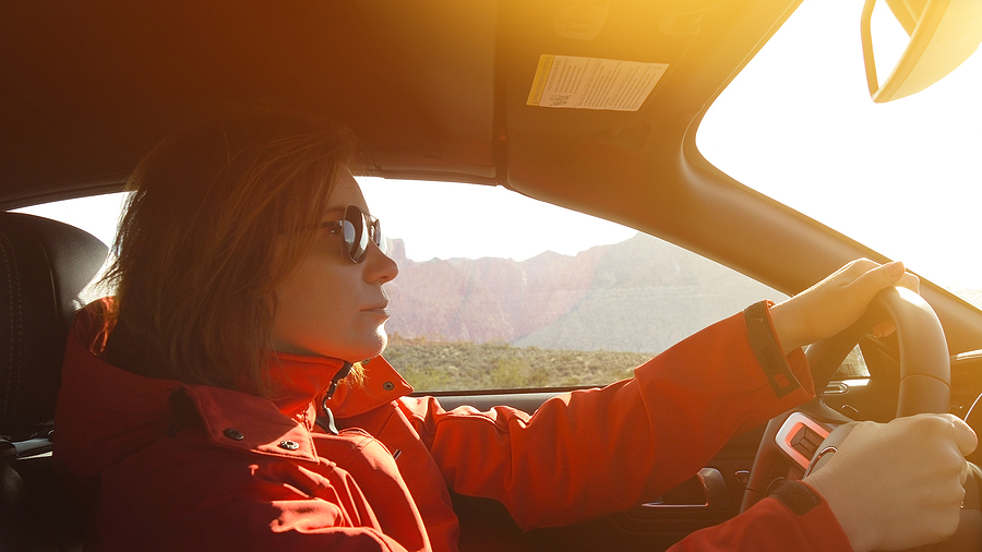 Image shows woman in driver’s seat, with both hands on steering wheel.