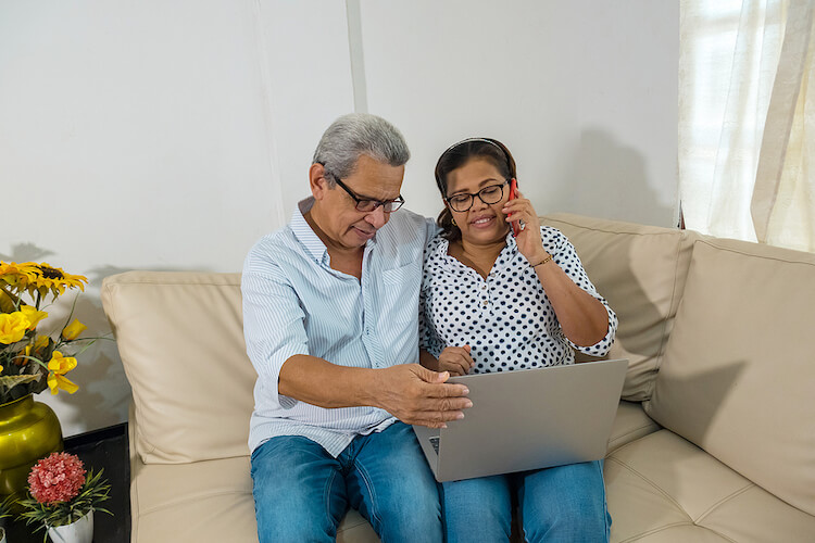 Older couple, with laptop, on phone with accessibility support.