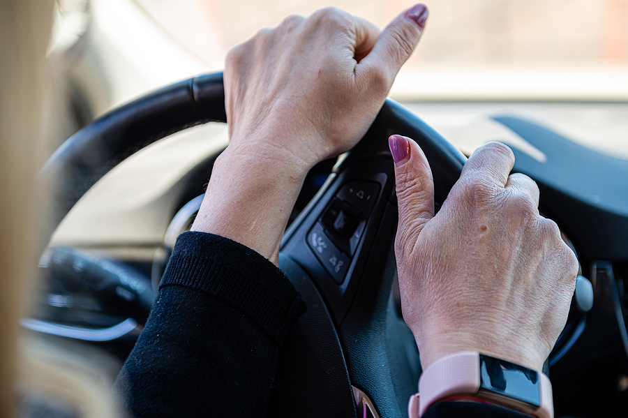 Close up of hands on steering wheel.