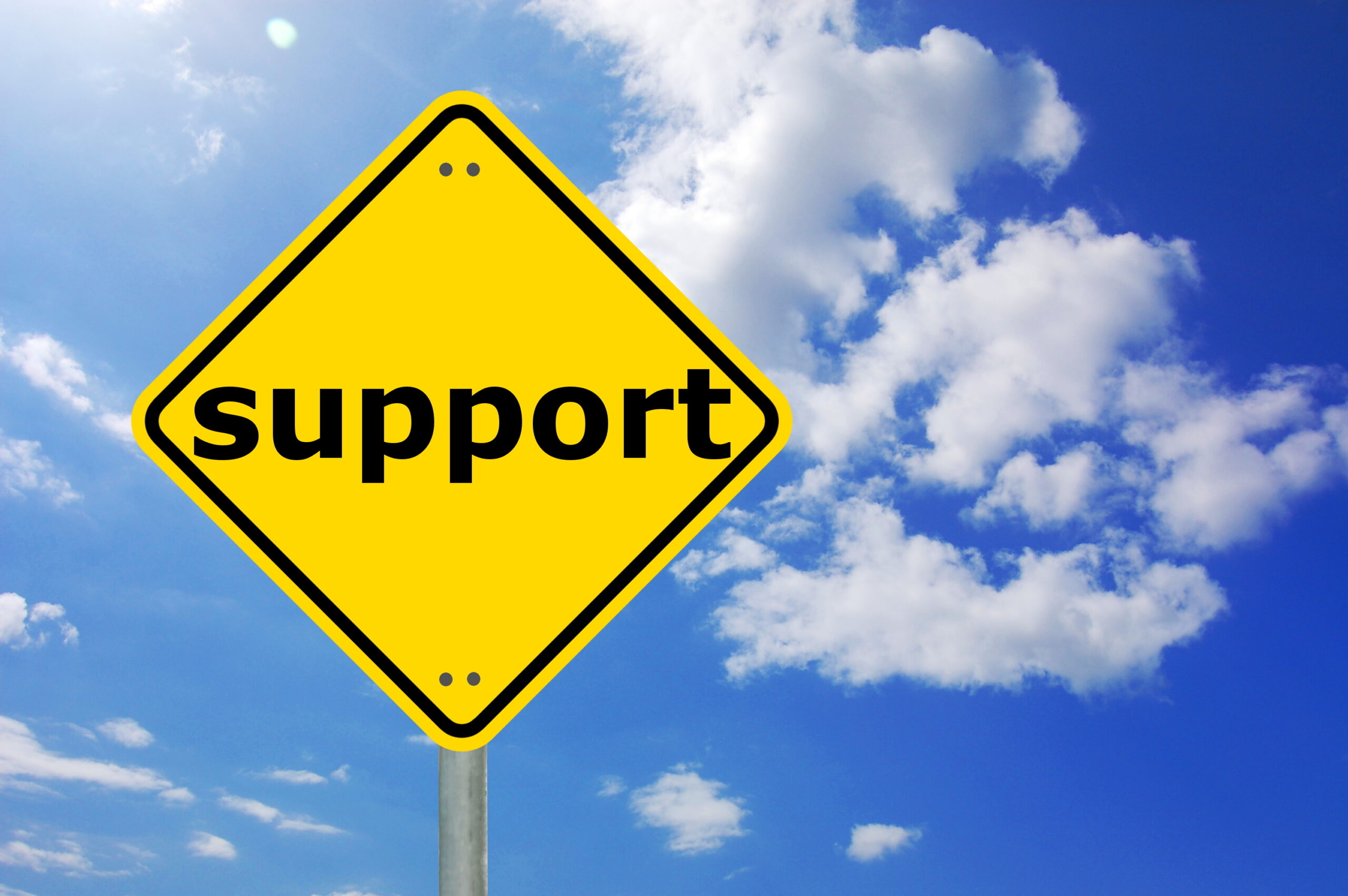 Yellow road sign for “Support” with clouds on blue sky in background