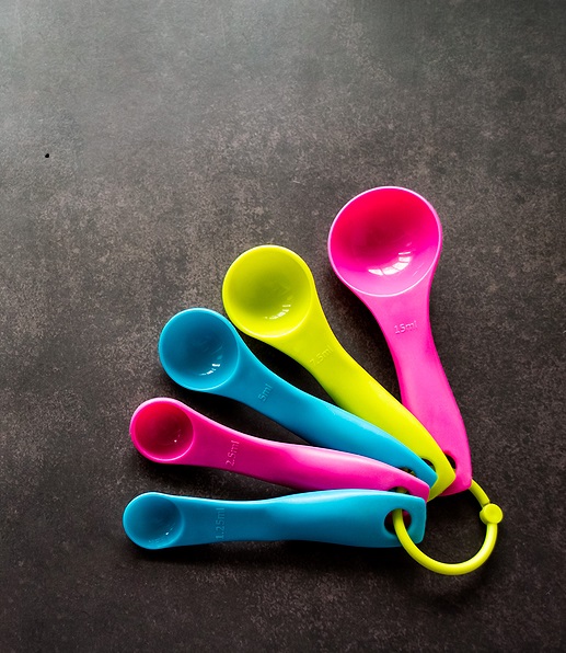 Multi-colored measuring spoons on black background.