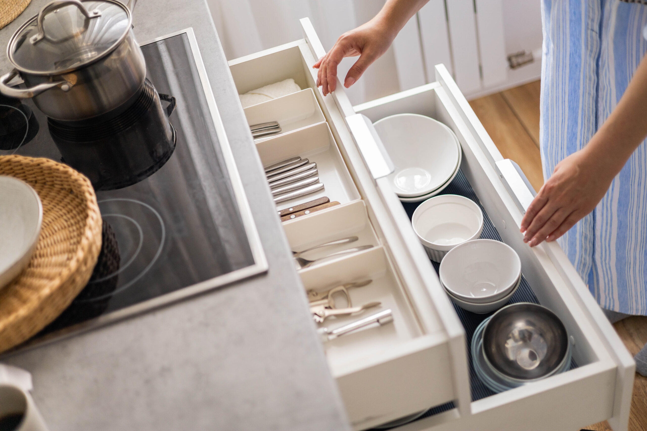 Hands reaching into organized kitchen drawers.