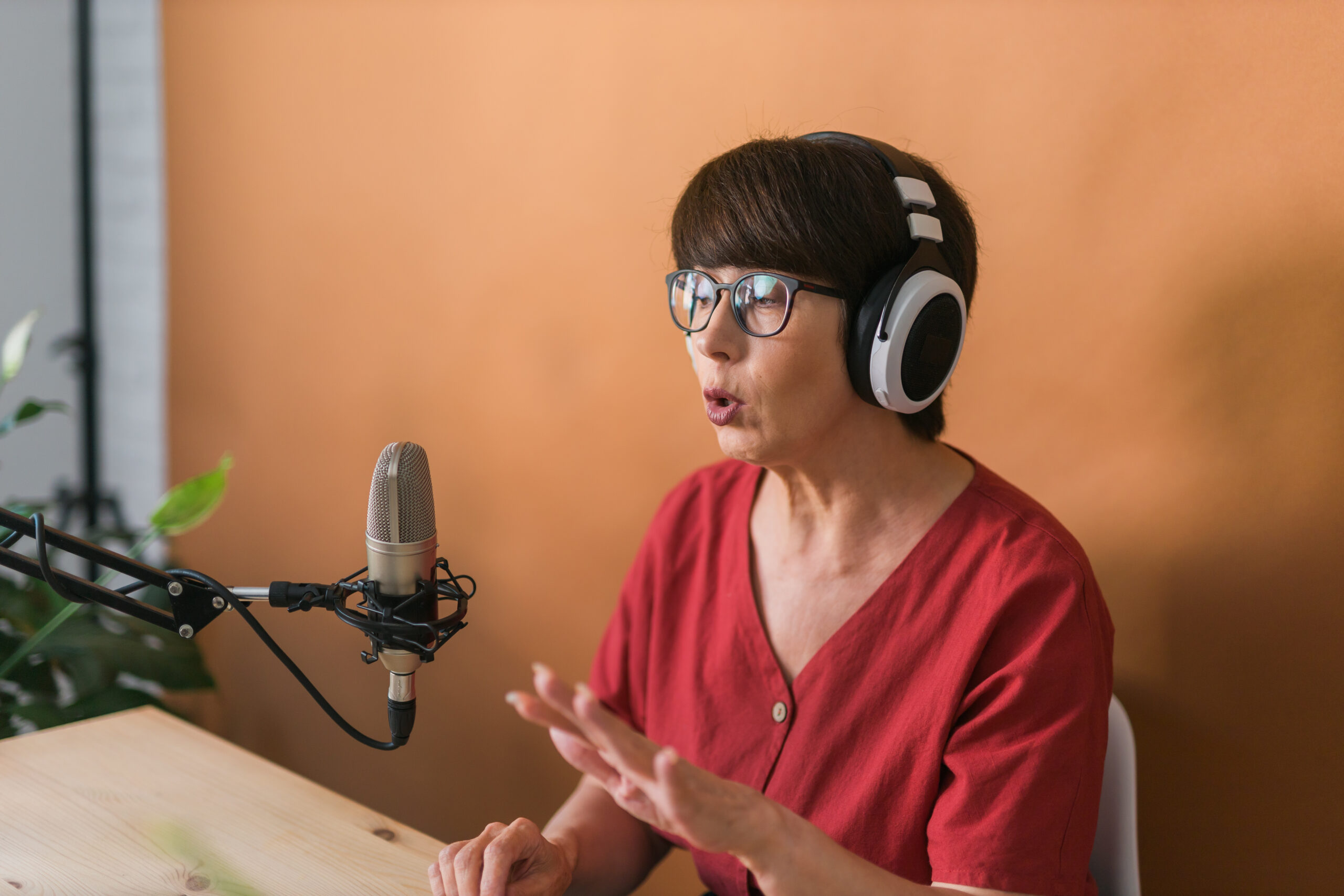 Woman with headphones and microphone recording audiobook