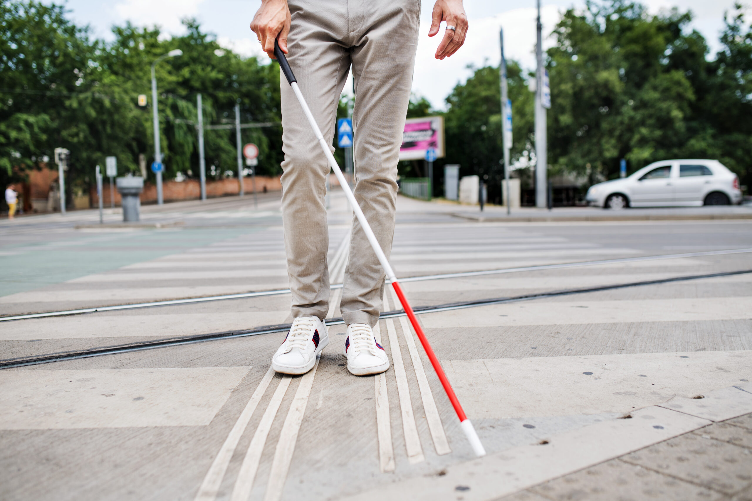 Visually impaired person with white cane crossing city street