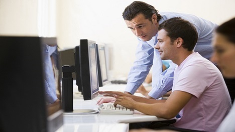 Business man helping a colleague on a computer