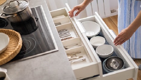 Hands reaching into organized kitchen drawers.