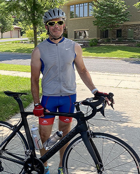 A man wearing helmet, standing with bike