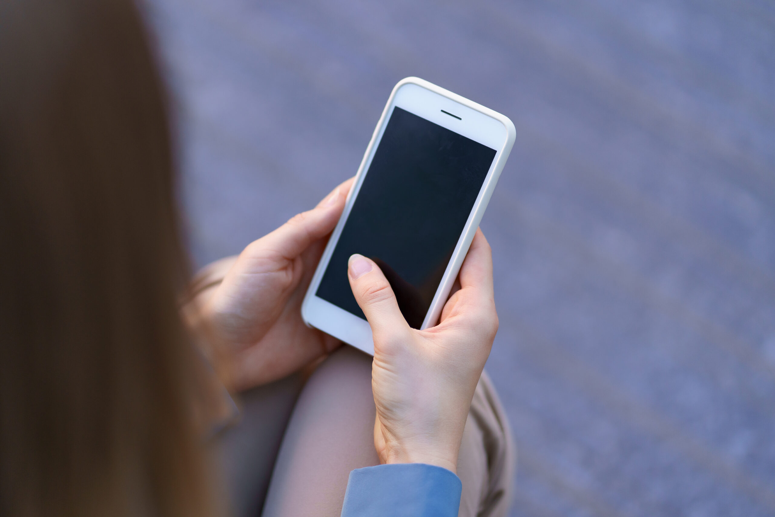 Hands holding smartphone with black screen