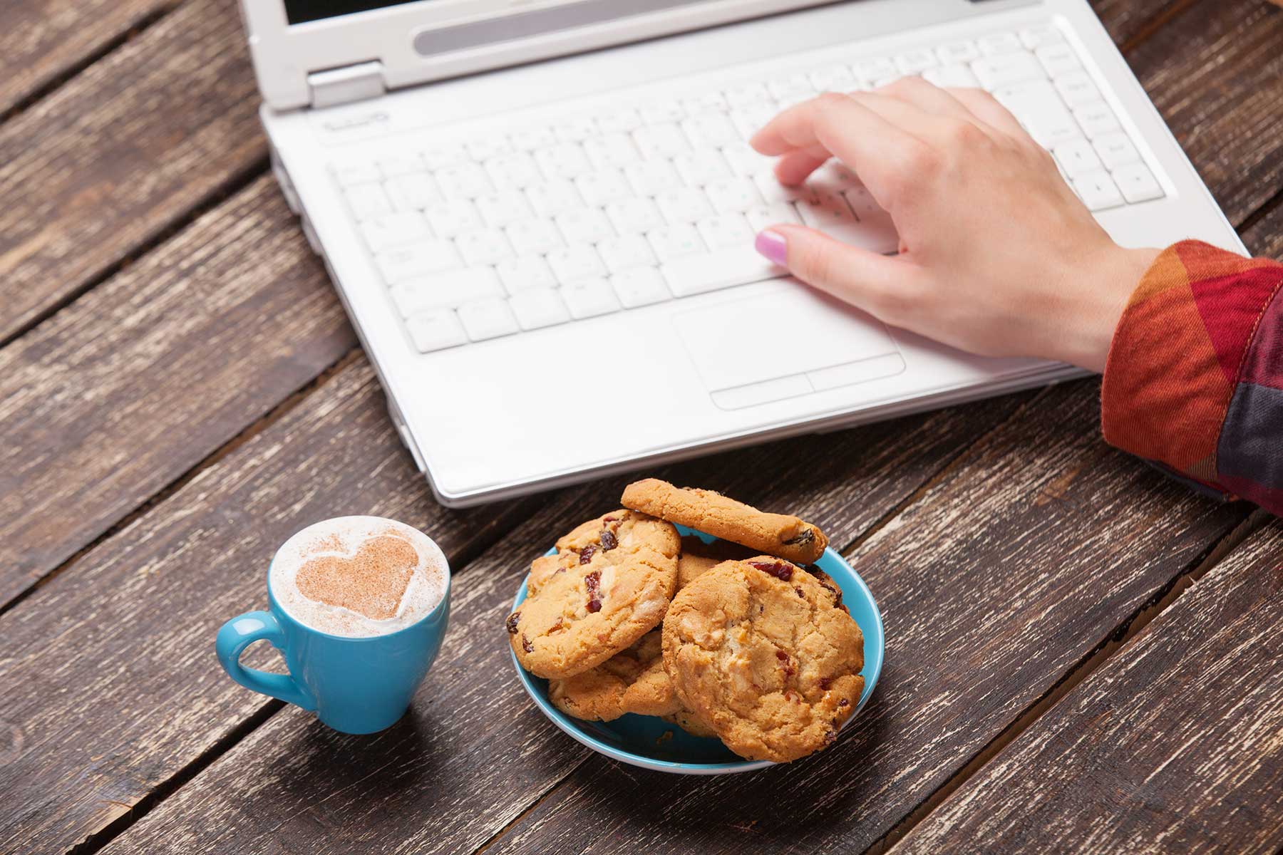 Cookies on plate placed in front of laptop keyboard