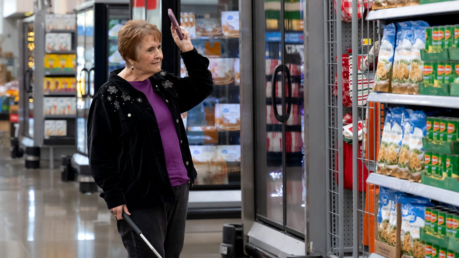 Walmart customer using white cane and smartphone with access to Aira for visual assistance