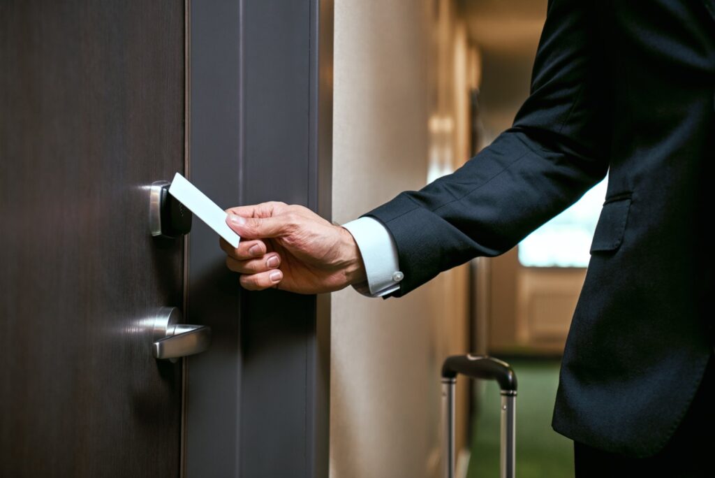 Hand with keycard opening hotel room door
